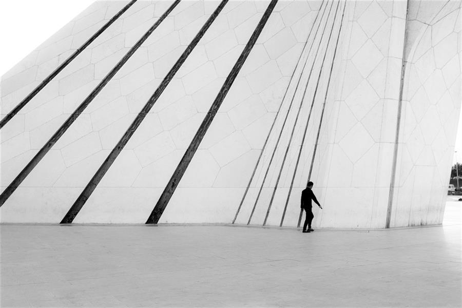 هنر عکاسی محفل عکاسی علی ذلقدری تصویر سایه و سفید در میدان ازادی و کنتراست بالای عکس،هماهنگی مرد عایر و خطوط سیاه باعث این ثبت شد